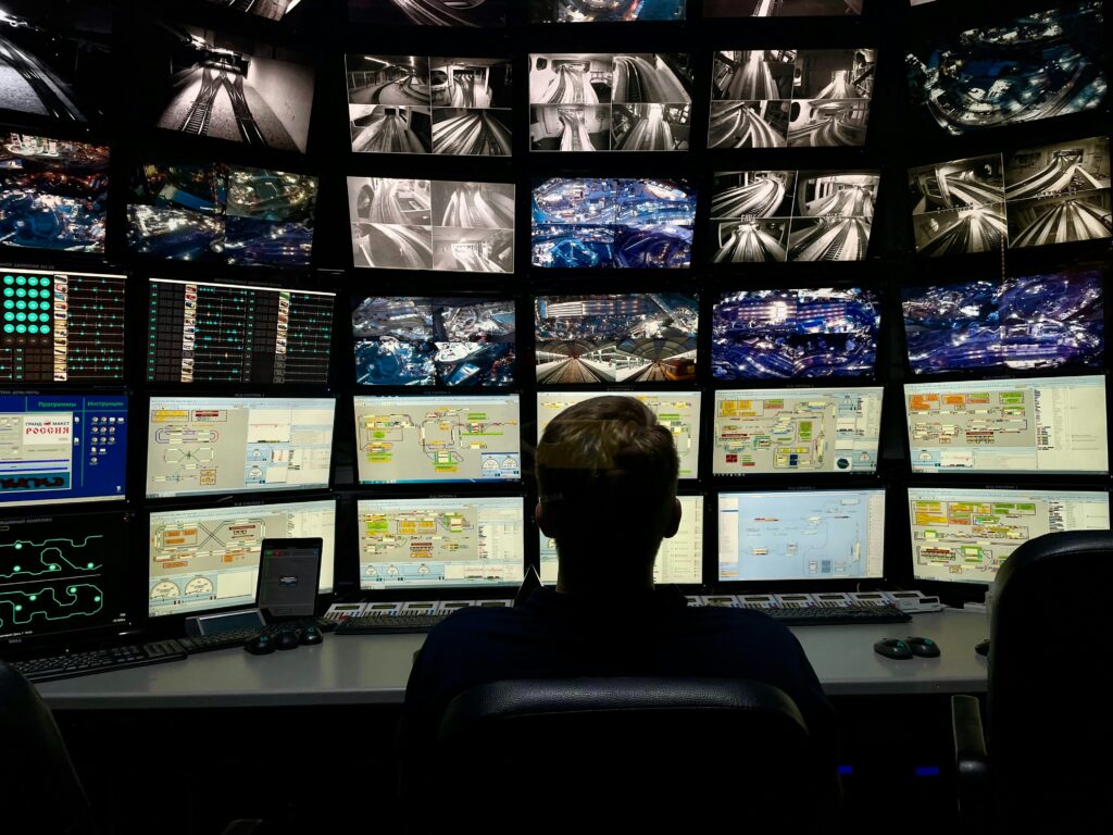Profissional analisando diferentes telas de computadores em ambiente de monitoramento de TI